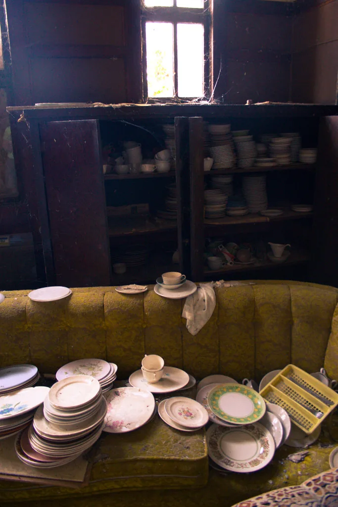 Muted ceramic cups and household objects against a dark cupboard.