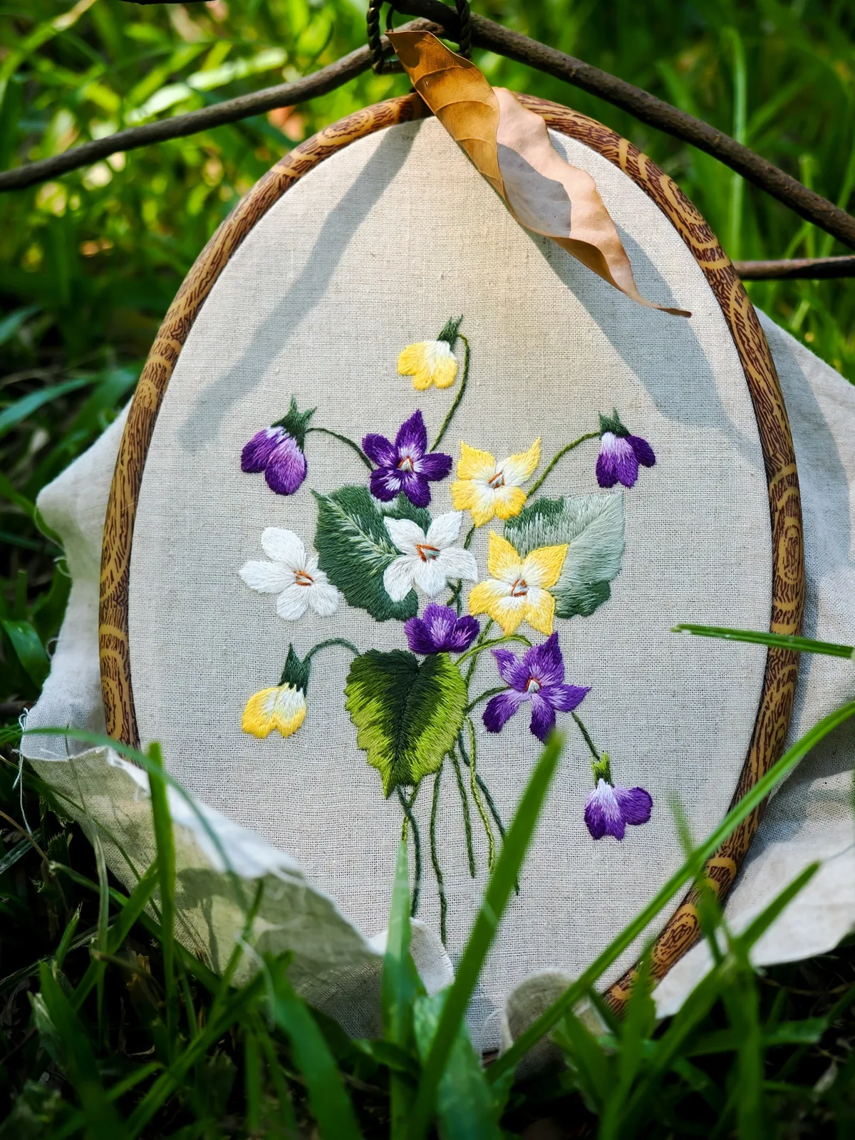 A hand-embroidered floral study held in a wooden hoop on linen.