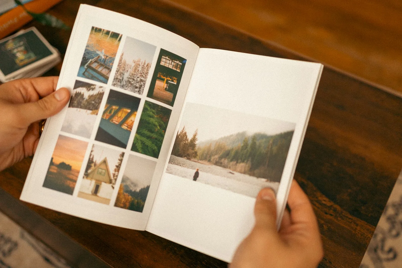 A reader holding a photographic publication open to a spread of images.