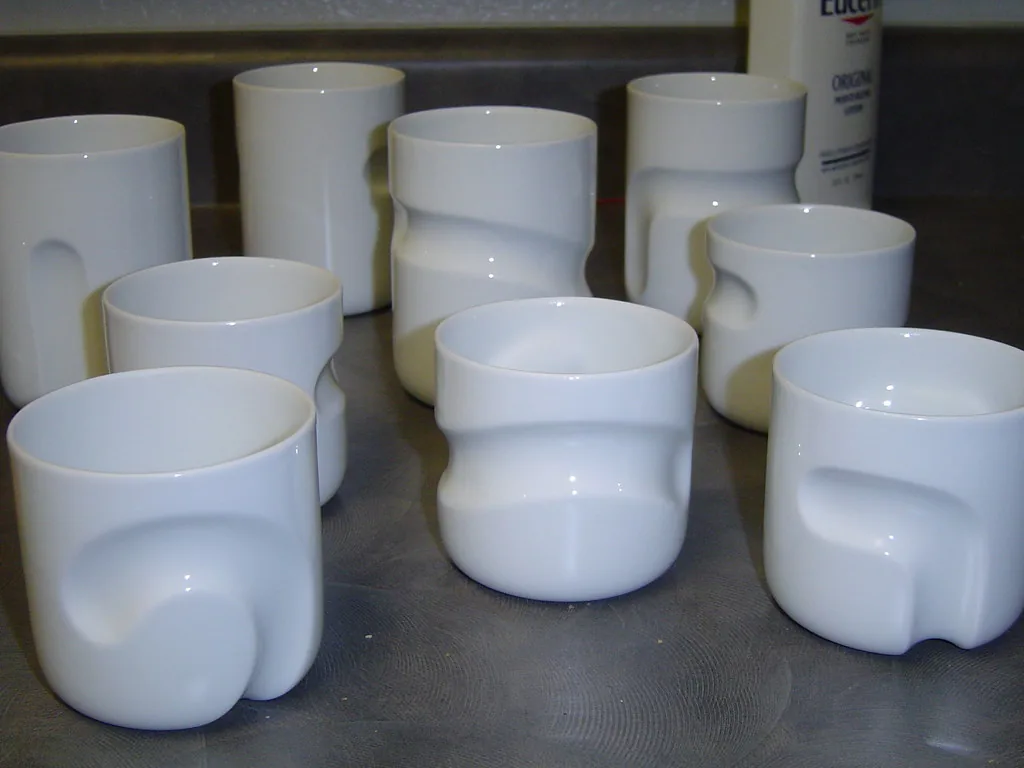 A group of plain white ceramic cups showing their rims and curved sides.