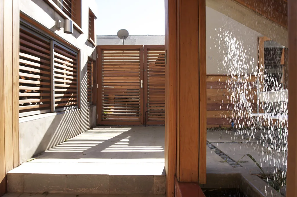 Sunlight and architectural shadows in a courtyard beside a recirculating rain window.