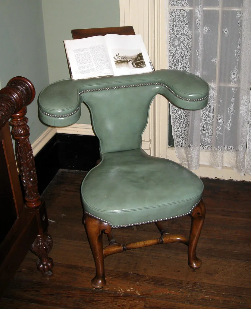 An old green upholstered wooden armchair with visible wear.