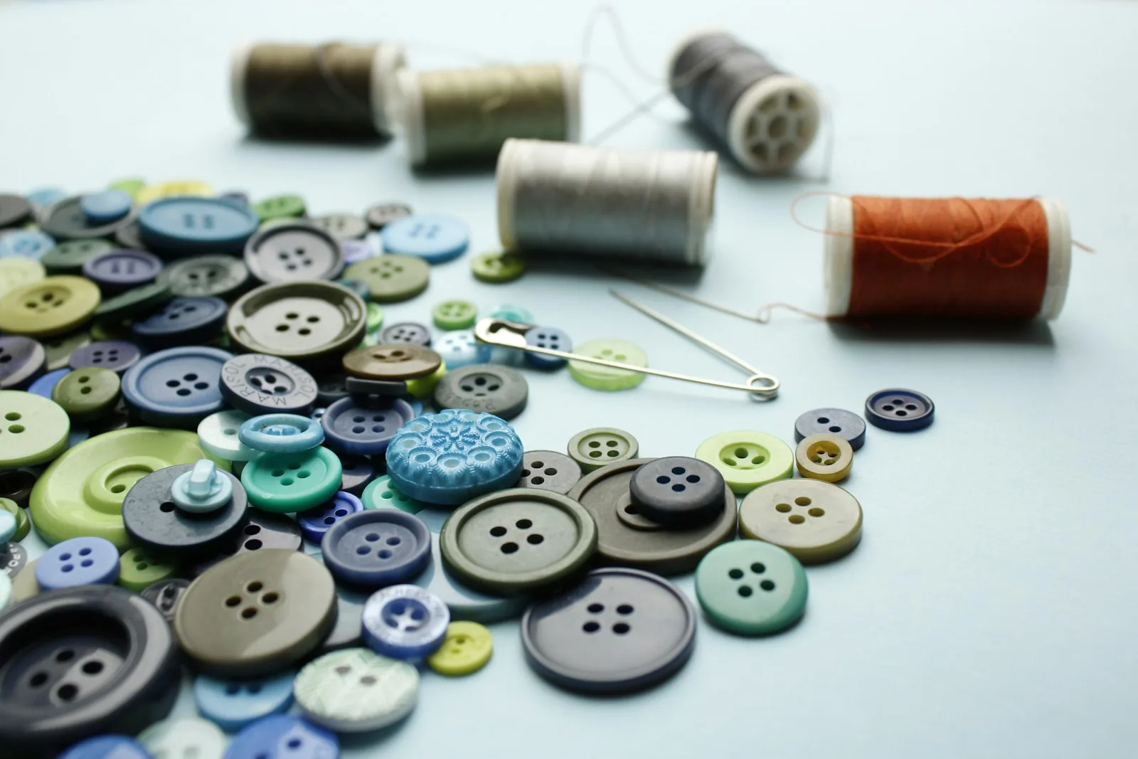 Buttons, sewing thread and hand-sewing supplies arranged on a surface.