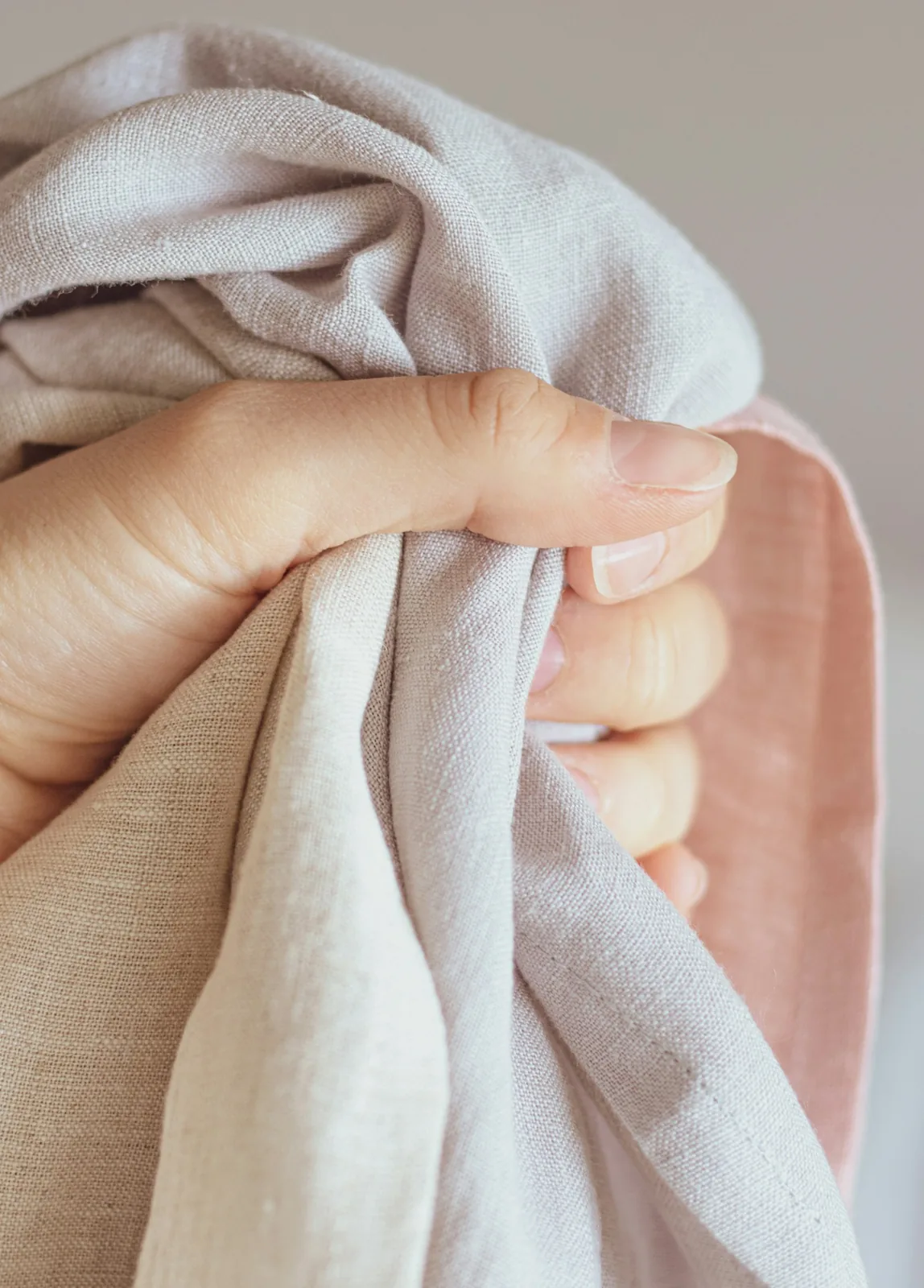 A person holding the edge of a softly draped household textile.