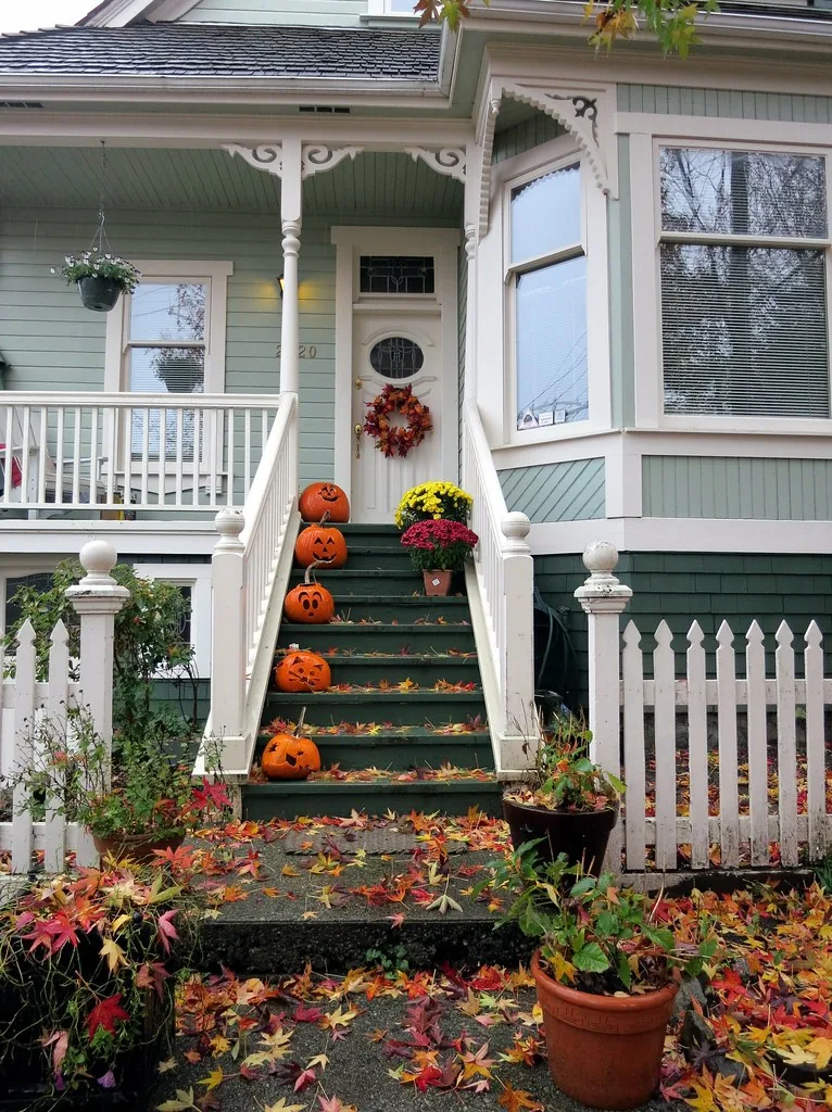 Pumpkins and seasonal plants arranged beside the steps of a house.